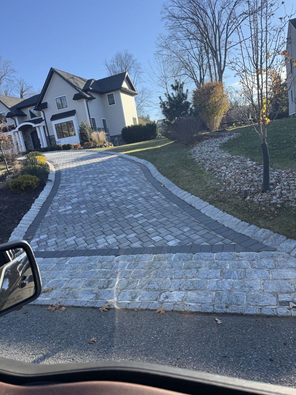 Completed paver driveway with stone border outside a New Jersey home